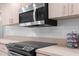 Close-up of modern stainless steel microwave and cooktop in the kitchen, with sleek tile backsplash at 8084 Nightingale Rd, Weeki Wachee, FL 34613