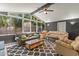 Bright living room showcasing vaulted ceilings, ceiling fan, and large windows offering views of the landscaped yard at 8634 Roble Way, Port Richey, FL 34668