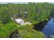 Aerial view showcases a wooded property with separate garage, driveway, and tranquil lake access at 8755 Marigold Dr, New Port Richey, FL 34654