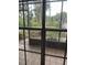 Enclosed back porch area featuring a tile floor with a view of the wooded backyard at 8755 Marigold Dr, New Port Richey, FL 34654