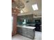 Spacious kitchen with gray wood cabinets, breakfast bar, tile floor, and an ornate chandelier at 8755 Marigold Dr, New Port Richey, FL 34654