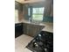 Kitchen featuring gray wood cabinets, stainless steel sink and faucet, black appliances, and a window with a wooded view at 8755 Marigold Dr, New Port Richey, FL 34654