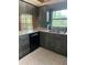 Kitchen featuring gray wood cabinets, stainless steel sink and faucet, black appliances, and a window with a wooded view at 8755 Marigold Dr, New Port Richey, FL 34654