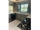 Kitchen featuring gray wood cabinets, stainless steel sink and faucet, black appliances, and a window with a wooded view at 8755 Marigold Dr, New Port Richey, FL 34654