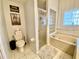 Well-lit bathroom featuring a glass-enclosed shower, soaking tub, and toilet at 9200 Turnberry Ct, New Port Richey, FL 34655
