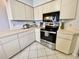 Well-lit kitchen featuring white cabinets, stainless steel appliances, and a tiled floor at 9200 Turnberry Ct, New Port Richey, FL 34655