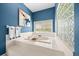 Modern bathroom with blue walls, tile floors, soaking tub, and a glass block window at 10044 Twelve Oaks Ct, Weeki Wachee, FL 34613