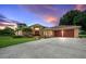 Exterior view of home featuring a brick facade, a two-car garage, well-maintained lawn, and dusk sky at 10044 Twelve Oaks Ct, Weeki Wachee, FL 34613