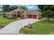 Exterior view of home featuring a brick facade, a two-car garage, and well-maintained lawn at 10044 Twelve Oaks Ct, Weeki Wachee, FL 34613