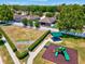 Aerial view of the community playground featuring a play structure, picnic pavilion and fenced green space at 10120 Ives Loop, Hudson, FL 34667