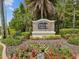 Beautiful community entrance sign with lush landscaping and colorful flowers creating a welcoming atmosphere at 10120 Ives Loop, Hudson, FL 34667
