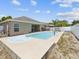 Backyard featuring a pool and jacuzzi, with a view of the house and lush vegetation around the fence at 10120 Ives Loop, Hudson, FL 34667