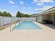 Backyard featuring a sparkling blue swimming pool, fenced-in area, and covered patio for relaxation at 10120 Ives Loop, Hudson, FL 34667
