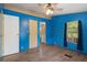 Bright bedroom with blue walls, ceiling fan, wood-look flooring and a window with natural light at 10149 Huntley St, New Port Richey, FL 34654