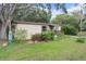 Exterior showcasing the house with a wooden ramp, mature trees, and a well-maintained lawn at 10149 Huntley St, New Port Richey, FL 34654