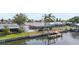 Waterfront home featuring a dock, boat lift, screened-in patio, and well-manicured lawn at 1024 Spindle Palm Way, Apollo Beach, FL 33572