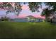 Dusk backyard view showcasing the house, enclosed pool area, and lush green lawn at 10250 Locker Dr, Spring Hill, FL 34608