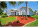 Beautiful home with vibrant landscaping, featuring red mulch, lush bushes, and a palm tree at 10250 Locker Dr, Spring Hill, FL 34608