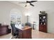 A home office with a large window, ceiling fan, and hardwood floors at 10250 Locker Dr, Spring Hill, FL 34608