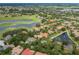 Aerial view of the neighborhood, showcasing homes nestled around a golf course and a scenic lake at 10531 Pontofino Cir, Trinity, FL 34655