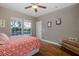 Comfortable bedroom with ceiling fan, two large windows, and rich-toned wood floors at 10531 Pontofino Cir, Trinity, FL 34655