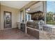 Outdoor kitchen with stainless steel grill, sink, mini-fridge, and stone accents at 10531 Pontofino Cir, Trinity, FL 34655