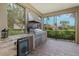 Outdoor kitchen with granite countertops, built-in grill, refrigerator, and stylish stone accents at 10531 Pontofino Cir, Trinity, FL 34655