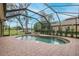 Screened-in pool area featuring a kidney shaped pool, brick pavers, and view of the yard and landscaping at 10531 Pontofino Cir, Trinity, FL 34655