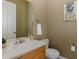 Half bathroom with neutral walls, sink, vanity, toilet and a hanging pineapple themed painting at 10531 Pontofino Cir, Trinity, FL 34655