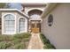 Elegant front entry featuring arched windows, double doors, and lush landscaping at 11404 Inman Ct, Spring Hill, FL 34609