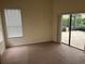 Spacious bedroom with carpet, a window, and sliding glass door to the screened lanai at 11520 Lounds Ct, New Port Richey, FL 34654