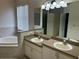 Bright bathroom featuring double sinks, a soaking tub, and a large window for a spa-like retreat at 11520 Lounds Ct, New Port Richey, FL 34654