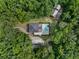 Aerial view of home with a pool surrounded by a stone patio and lush, mature trees at 12085 Stringer Rd, Brooksville, FL 34601
