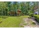 Expansive backyard with a rustic cabin, lush greenery, and manicured landscaping at 12085 Stringer Rd, Brooksville, FL 34601