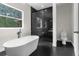Bright bathroom features standalone tub next to a window with a black-tiled shower room at 12085 Stringer Rd, Brooksville, FL 34601