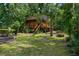 Cozy cabin with wooden exterior surrounded by lush greenery and tall trees at 12085 Stringer Rd, Brooksville, FL 34601