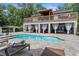 A beautiful in-ground pool with a lounge area, a covered patio, and luscious landscaping in the backyard at 12085 Stringer Rd, Brooksville, FL 34601