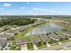 Wide aerial view of a lakeside neighborhood, with homes nestled around a picturesque lake and green spaces at 12313 Criollo Rd, Spring Hill, FL 34610