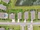 Overhead aerial view of homes with well-kept yards near a pond and wooded landscape at 12313 Criollo Rd, Spring Hill, FL 34610