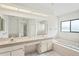 Bright bathroom featuring double sinks, large mirror, bathtub, and natural light at 128 Oak Lake Dr, Spring Hill, FL 34608