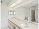 Bright bathroom features a double sink vanity, large mirror, and neutral tile flooring at 128 Oak Lake Dr, Spring Hill, FL 34608
