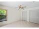 Neutral bedroom with window and double closets features neutral tile flooring and a ceiling fan at 128 Oak Lake Dr, Spring Hill, FL 34608