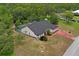 Aerial view of house featuring a screened in pool, red driveway, and mature trees at 128 Oak Lake Dr, Spring Hill, FL 34608