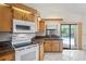 Well-lit kitchen with white appliances, tile flooring, and a view of the outdoor pool at 128 Oak Lake Dr, Spring Hill, FL 34608
