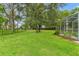 Expansive backyard featuring lush green grass, mature trees, and a black fence for privacy at 12805 Coronado Dr, Spring Hill, FL 34609