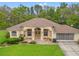 Charming single-story home featuring a manicured front lawn, neutral color palette, and an attached two-car garage at 12805 Coronado Dr, Spring Hill, FL 34609