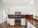 Modern kitchen with white cabinetry, stainless steel appliances, and dark wood floors at 13922 Talmage Loop, Hudson, FL 34667
