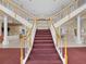 Elegant, dual staircase with white railings, wood trim and a plush, red carpet runner at 13922 Talmage Loop, Hudson, FL 34667