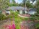 Charming home featuring meticulous landscaping with mature trees, lush flower beds, and a neatly manicured lawn at 1471 N Jasmine Ave, Tarpon Springs, FL 34689