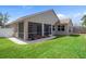Home's screened-in porch leads to the backyard, landscaped with rocks and mulch, and a grassy lawn at 1862 Wood Bend St, Tarpon Springs, FL 34689
